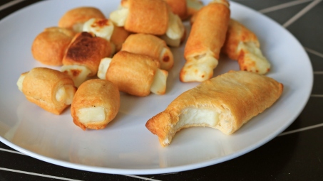 Cheese in pastry blankets on a white plate.